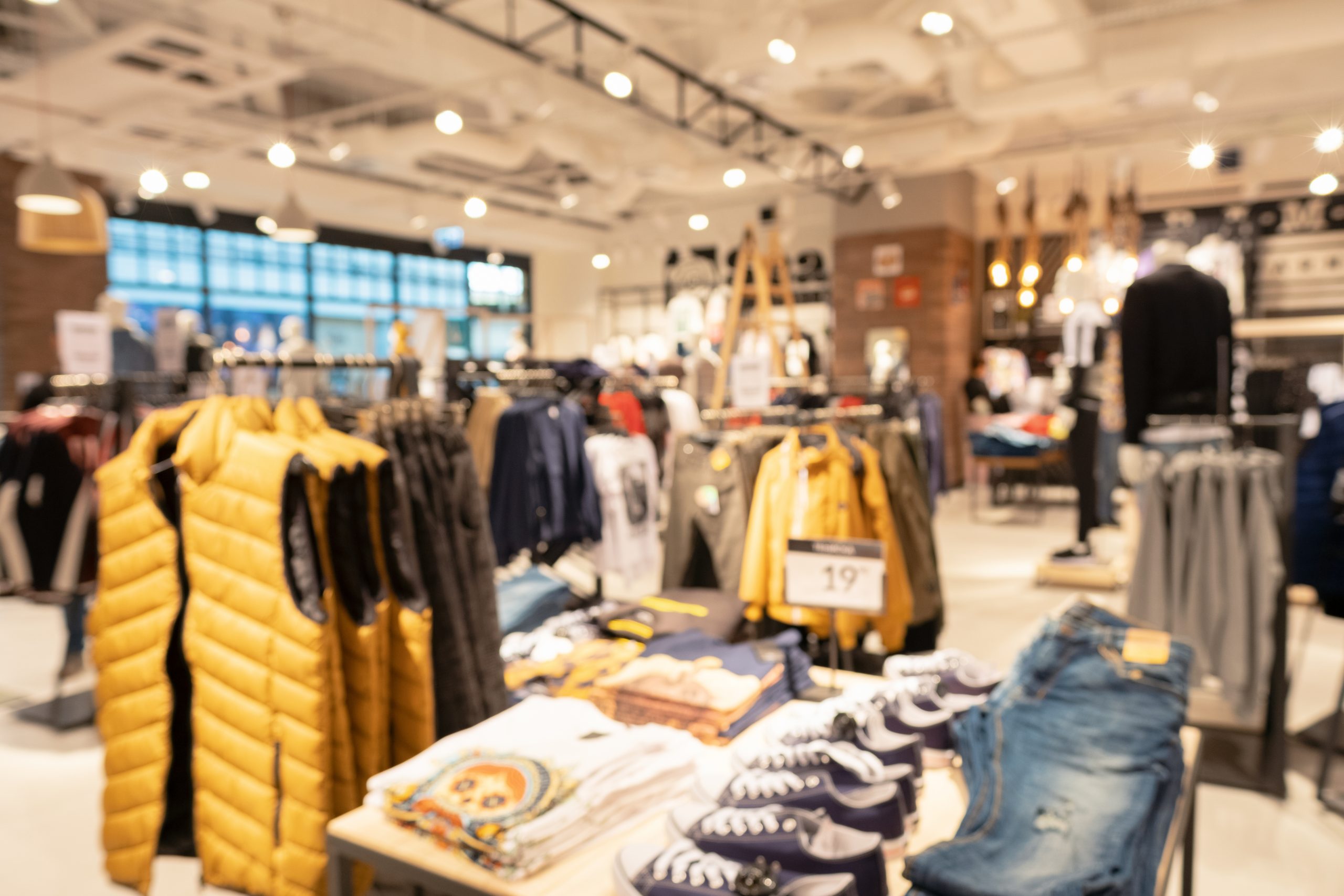 Blurred big sales on Black Friday. On sale in a clothing store in a modern shopping center. Beautifully laid out things on hangers and mannequins. Shopping. Main background for design. Copyspace